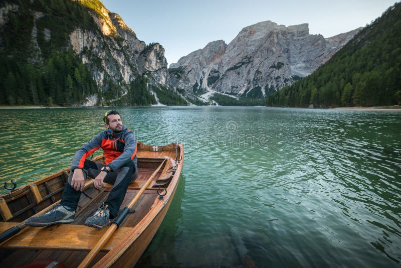 Man seating on boat on lago di braies, italien dolomites, travel and adventure photography