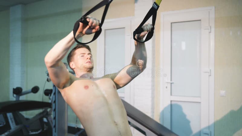 A man shaking hands in the hall TRX, a man doing exercises on his hands