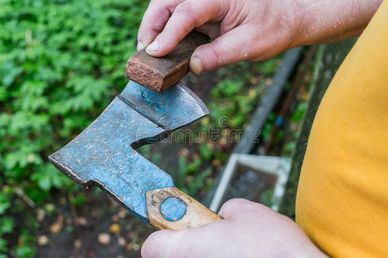 A Man is Sharpening an Ax with a Grindstone Stock Photo Image of