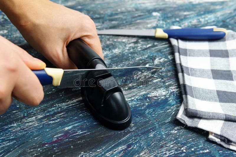 Man Sharpening a Knife on a Grindstone in the Kitchen, Mans Work Stock