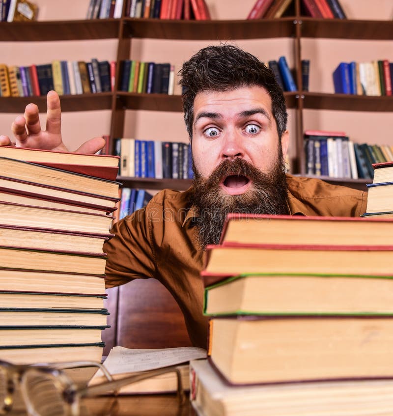 Man on Shocked Face between Piles of Books, while Studying in Library