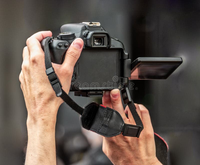 A man shoots video over a crowd holding a DSLR camera