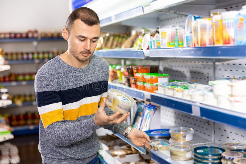 Man Shopper Carefully Selects Salted Herring in Grocery Store Stock