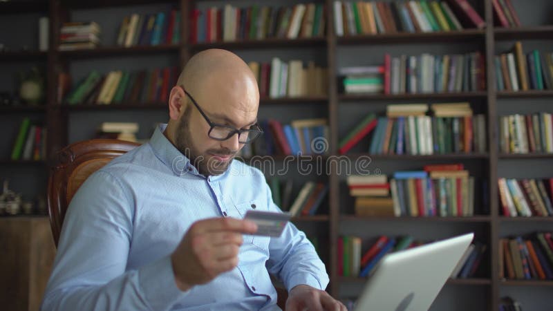 Man shopping online with credit card. Young man using credit card online with his laptop at home on the background of stock video