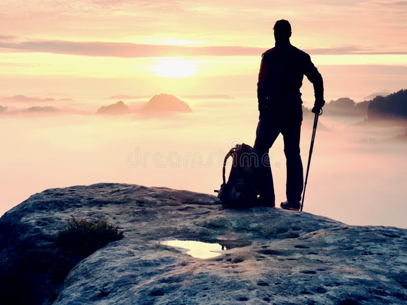 Man silhouette stay on sharp rock peak. Satisfy hiker enjoy view. Tall man on rocky cliff stock photography Man silhouette stay on sharp rock peak. Satisfy hiker enjoy view. Tall man on rocky cliff stock photography