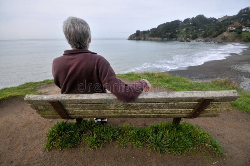 Man sits on a bench above the ocean