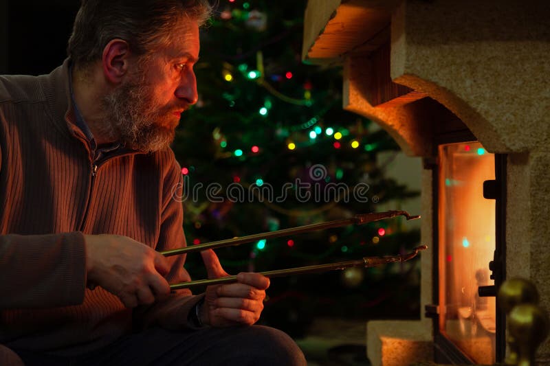 Man sits in front of burning fireplace. Behind Christmas tree royalty free stock images
