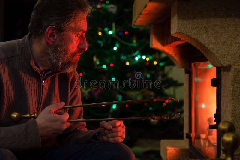 Man sits in front of burning fireplace. Behind Christmas tree royalty free stock images
