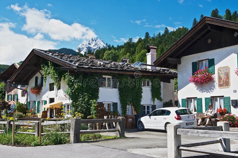 Man sits in front of the traditional bavarian house in Mittenwald, Germany.