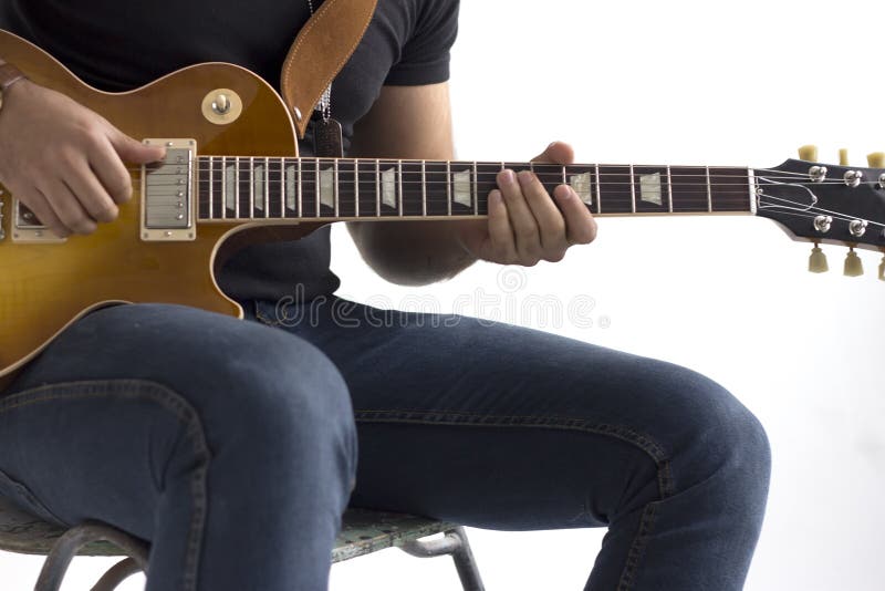 A man is sitting on a chair and playing an electric guitar on a white background.