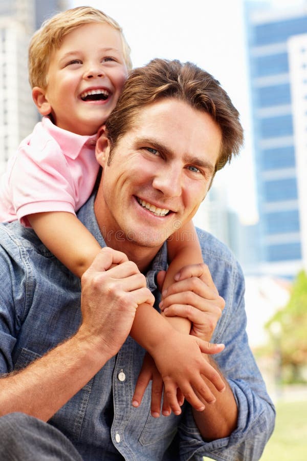 Man sitting in city park with young son