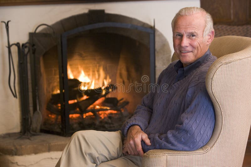 Man sitting in living room by the fireplace smiling