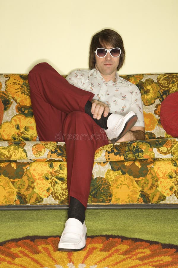 Man sitting on sofa. Caucasian mid-adult man sitting on colorful retro sofa wearing sunglasses looking bored stock images Man sitting on sofa. Caucasian mid-adult man sitting on colorful retro sofa wearing sunglasses looking bored stock images
