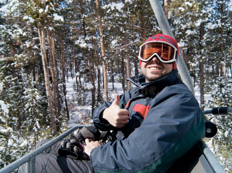 Man skier on chairlift in forest