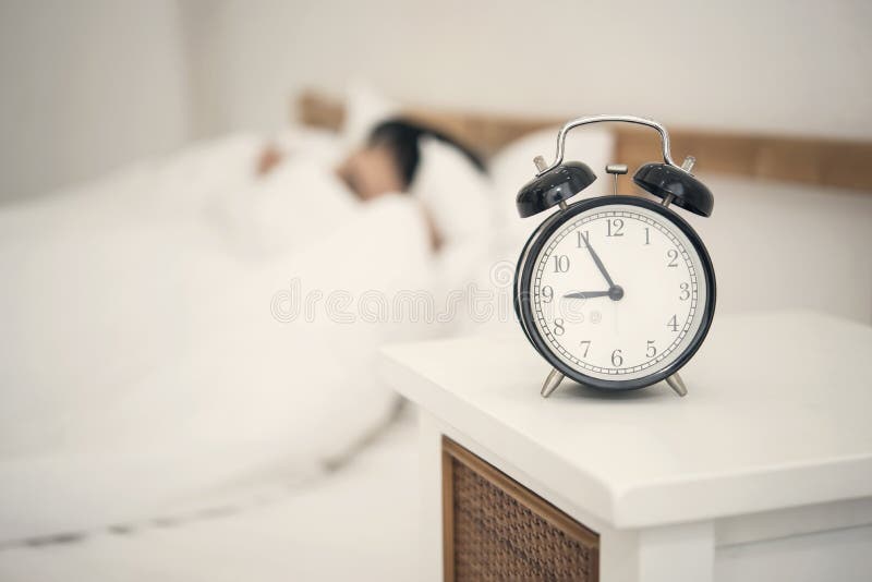 Man sleeping on bed in bedroom and alarm clock.