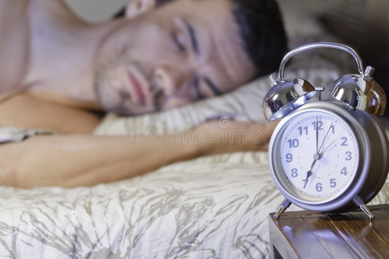 A man sleeping close to a retro alarm clock