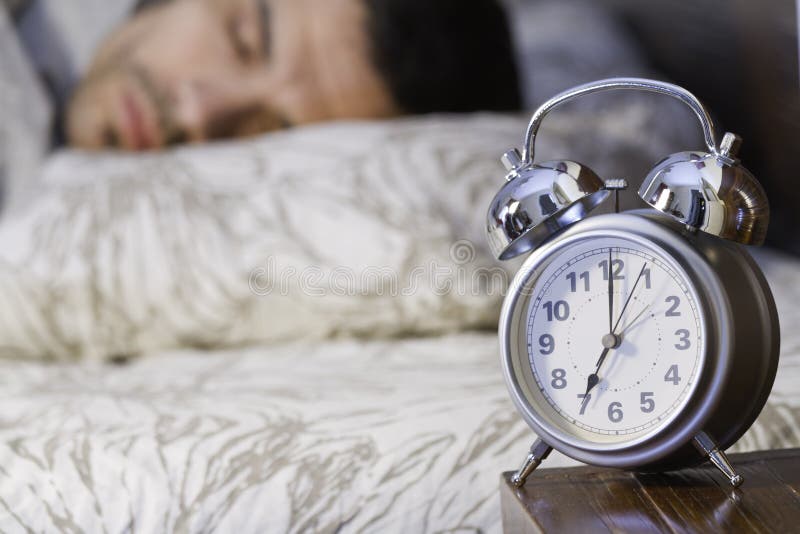 A man sleeping close to a retro alarm clock