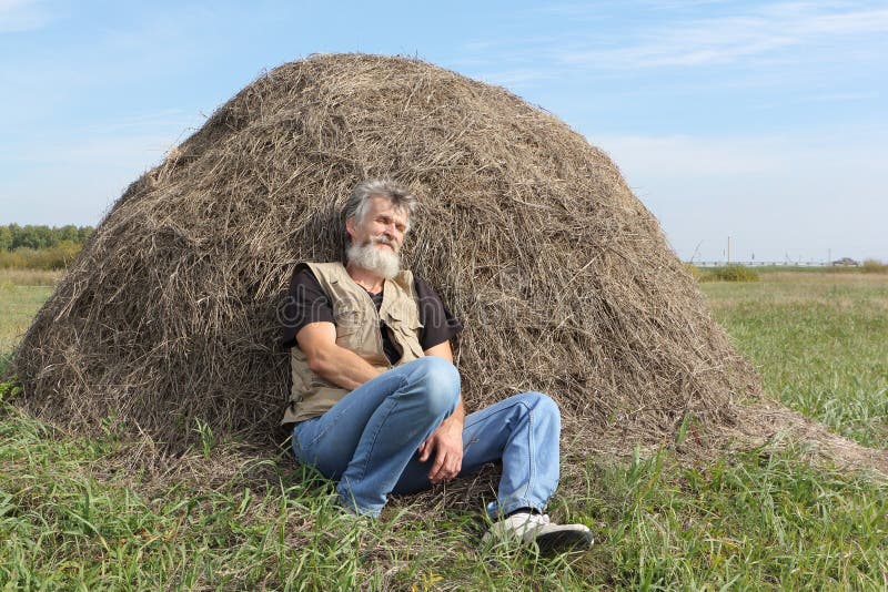 Man sleeping in a field near a haystack in the fall. 