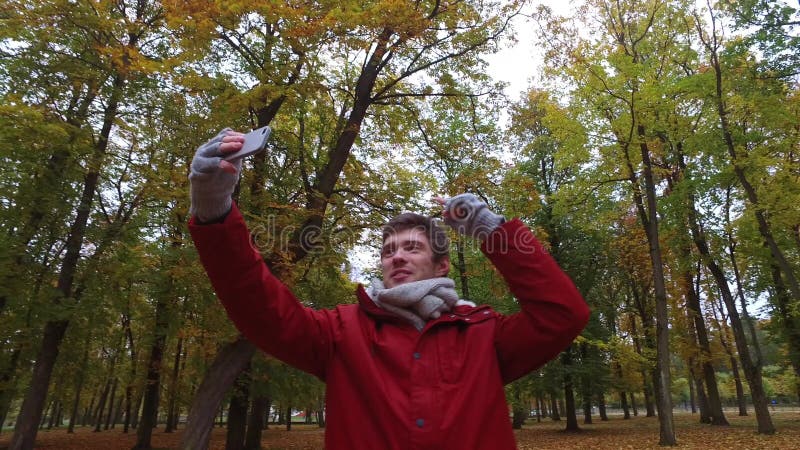 Man with smartphone taking video at autumn park