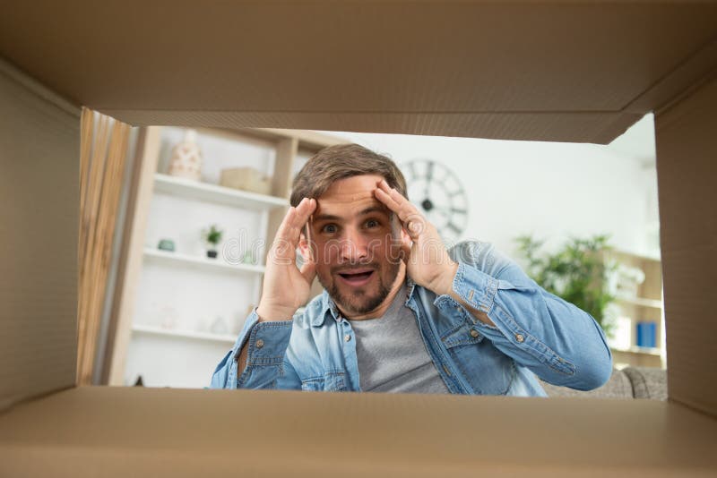 Man smiling unpacking opening carton box and looking inside stock image Man smiling unpacking opening carton box and looking inside stock image