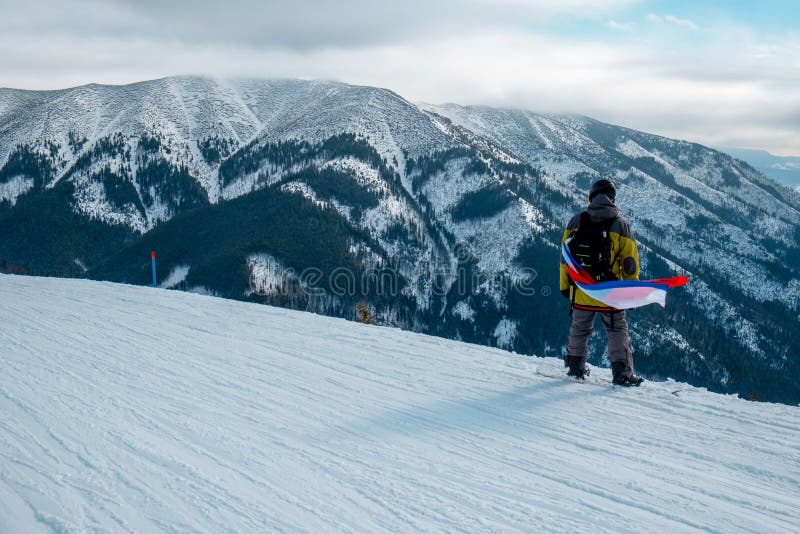 Muž snowboardista so slovenskou vlajkou na svahu lyžiarskeho strediska