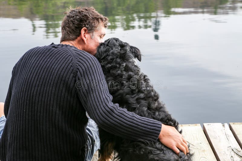 Man snuggles dog at lake