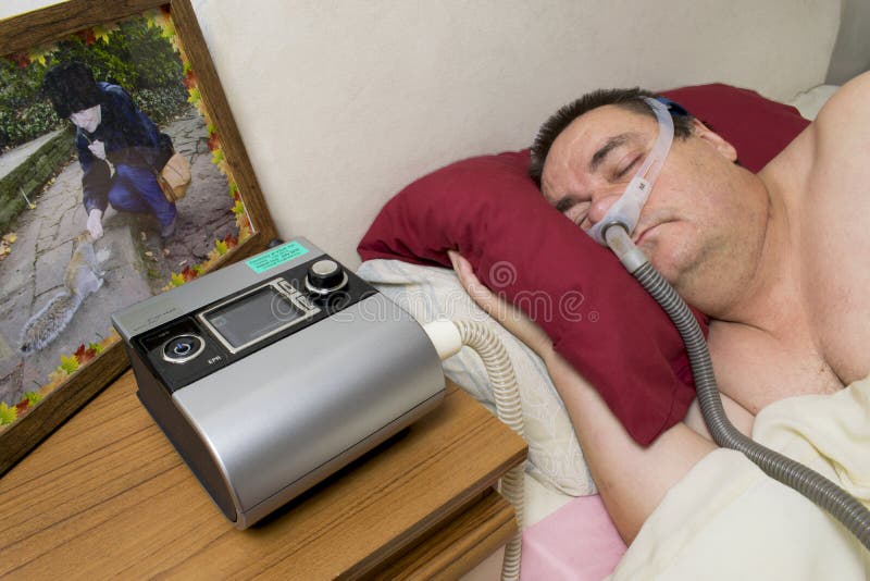 Man som använder CPAP-maskinen och sover maskeringen för behandling av sömn arkivbild Man som använder CPAP-maskinen och sover maskeringen för behandling av sömn arkivbild