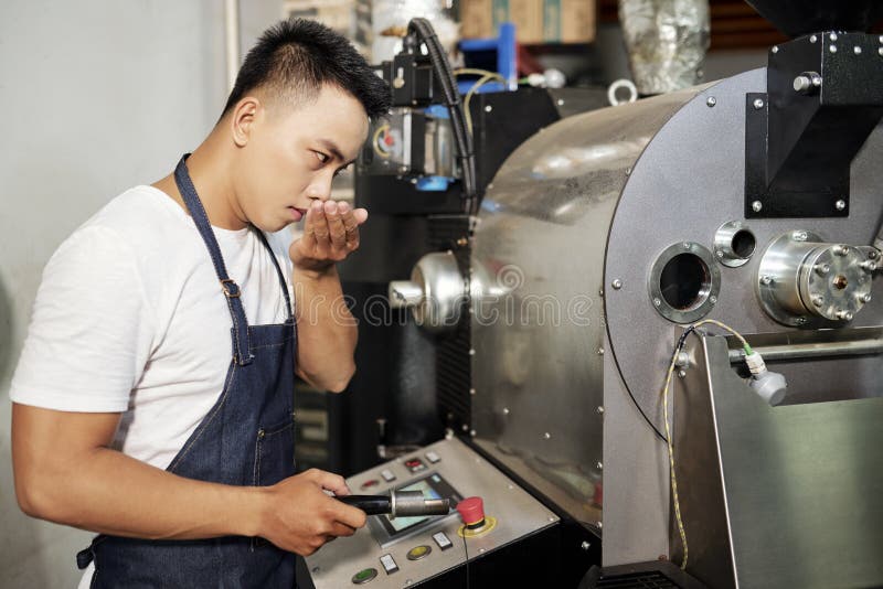 Man som arbetar i produktionen av att grilla kaffe arkivbild Man som arbetar i produktionen av att grilla kaffe arkivbild