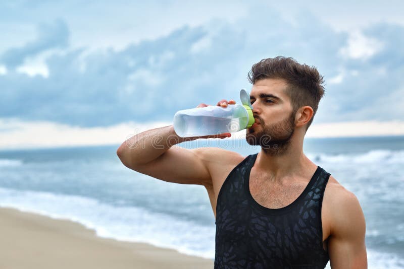 Man som dricker uppfriskande vatten efter genomkörare på stranden drink arkivbilder Man som dricker uppfriskande vatten efter genomkörare på stranden drink arkivbilder
