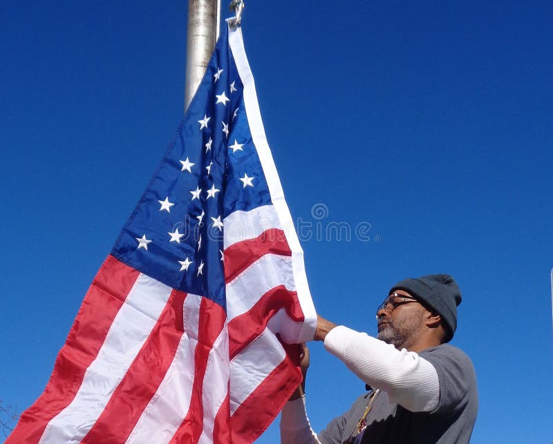 Man som lyfter amerikanska flaggan fotografering för bildbyråer Man som lyfter amerikanska flaggan fotografering för bildbyråer