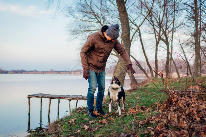 Man speelt met hond in herfstpark door meer Gelukkig huisdier met plezier buitenshuis springen royalty-vrije stock afbeeldingen Man speelt met hond in herfstpark door meer Gelukkig huisdier met plezier buitenshuis springen royalty-vrije stock afbeeldingen