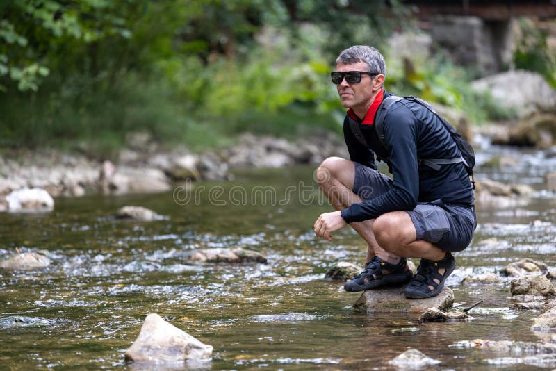 Man Squatting beside River in Forest Stock Photo Image of leisure
