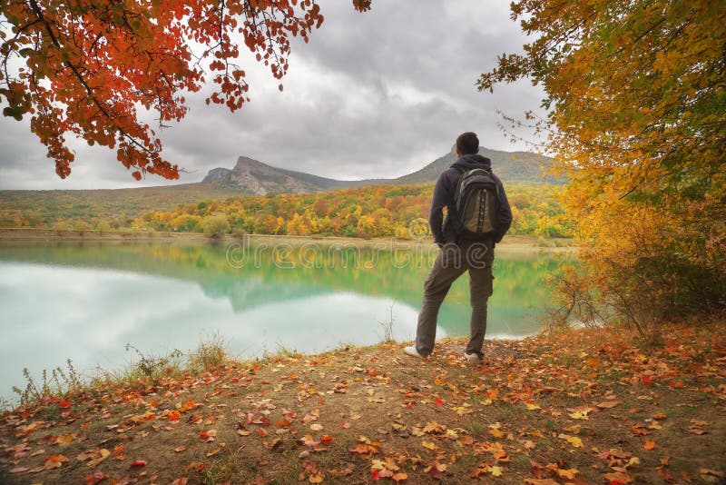 Man standing alone on the autumn pond