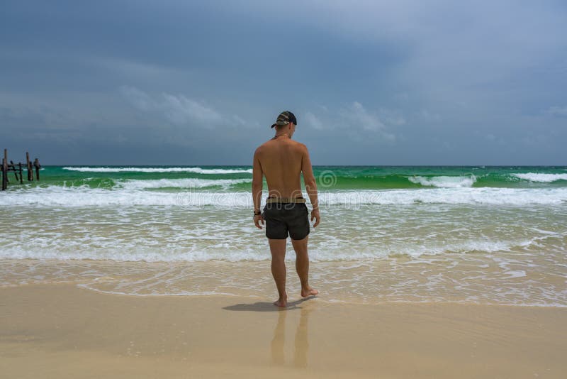 Man standing at the beach and watching the ocean stock photography