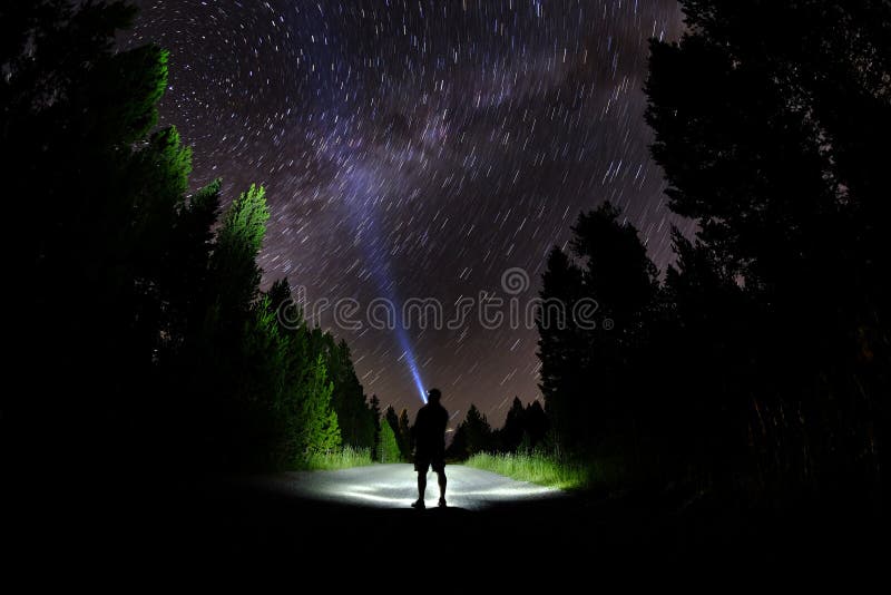 Man Standing in Dark Stars with Flashlight Forest Night Sky