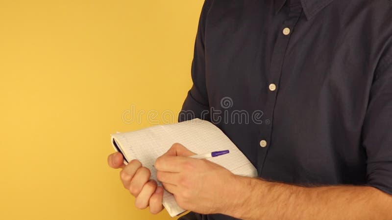 A man standing in half turn makes notes in a notebook