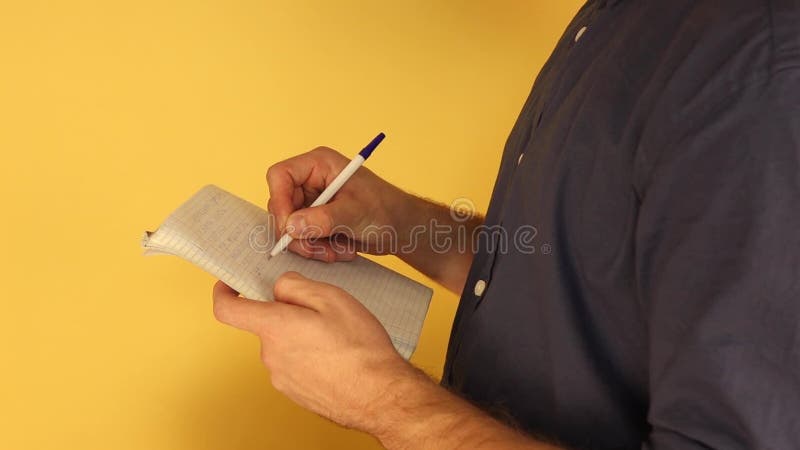 A man standing in half turn makes notes in a notebook