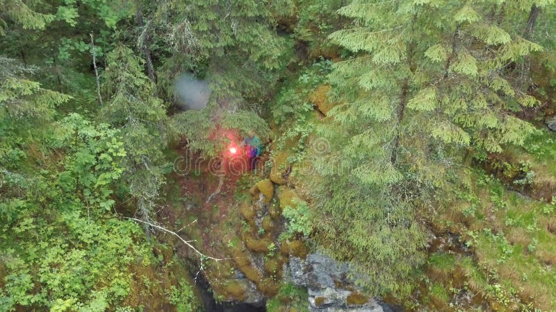 Man standing near the deep ravine with red signal flare in his hand in forest near the high old trees and shrubs. Stock stock photography Man standing near the deep ravine with red signal flare in his hand in forest near the high old trees and shrubs. Stock stock photography