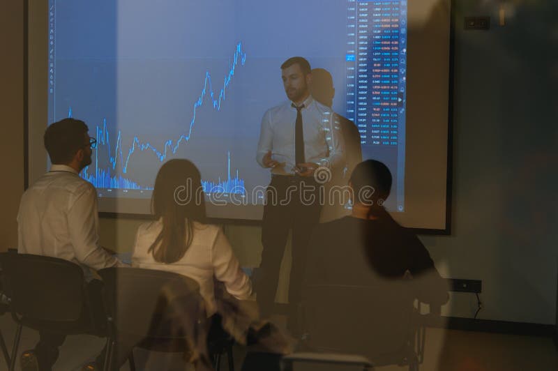 Man is standing near projector and showing graphs and business graphs.