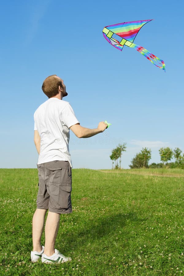 Man standing on summer meadow and flying kite