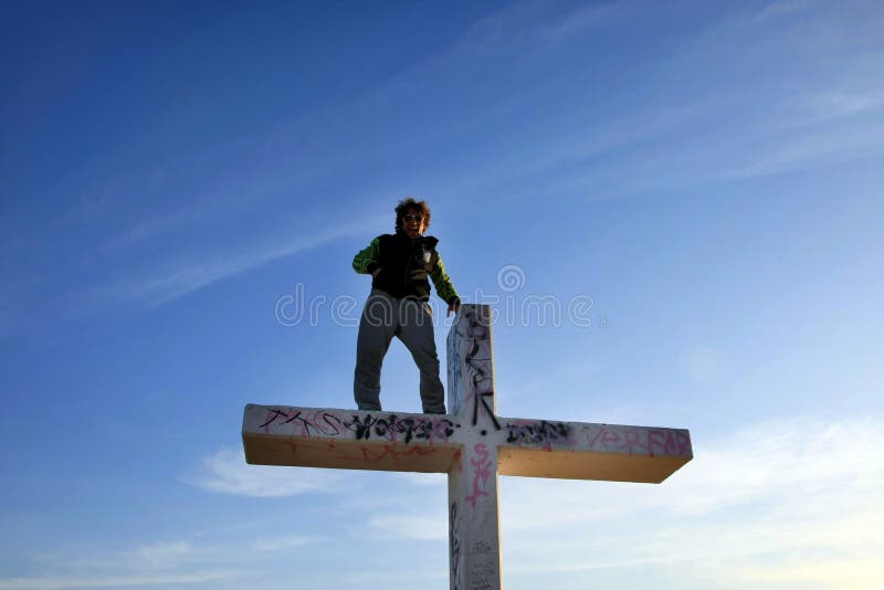 Man Standing on Tall Cross