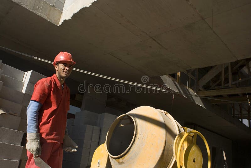 Man Stands Next to Cement Mixer - Horizontal