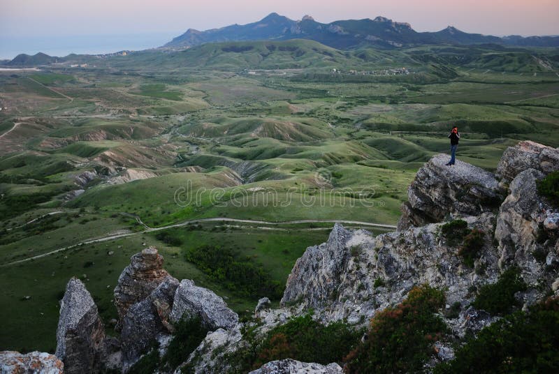 Man stands on a rocky peak against a green valley royalty free stock images Man stands on a rocky peak against a green valley royalty free stock images