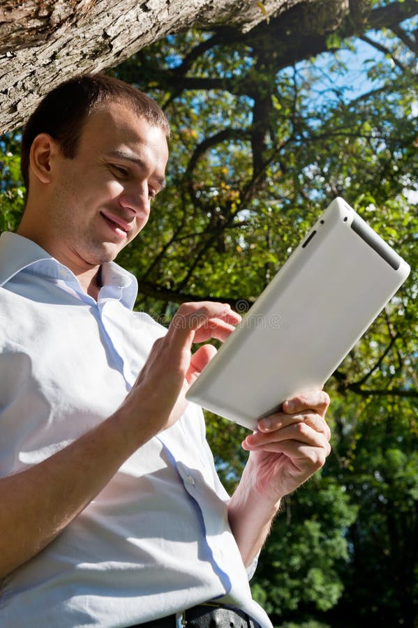 Man stands with tablet near the tree