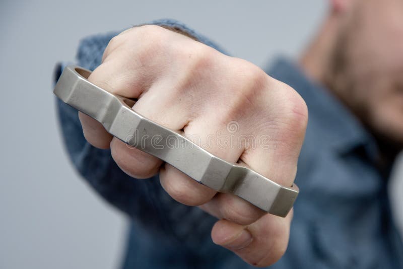 A man strikes a brass knuckles on a light background, a street gang of hooligans