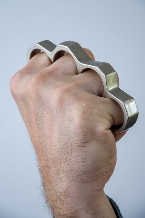 Man Strikes Brass Knuckles on a Light Background, a Prohibited