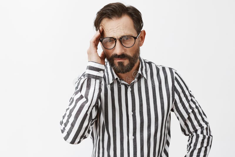 Man stuck in bad situation, thinking up way out. Portrait of intense serious-looking upset guy, holding fingers on temple and staring with frowned eyebrows at camera, feeling discomfort. Copy space