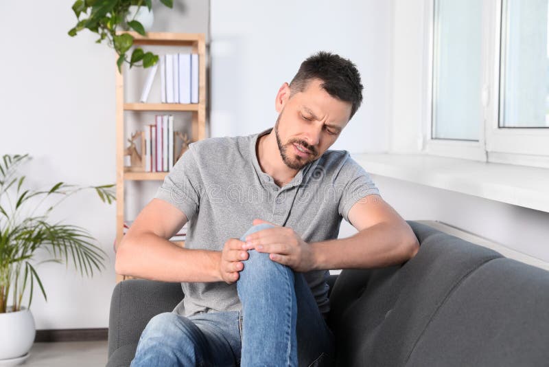 Man Suffering from Knee Pain on Sofa at Home Stock Image Image of