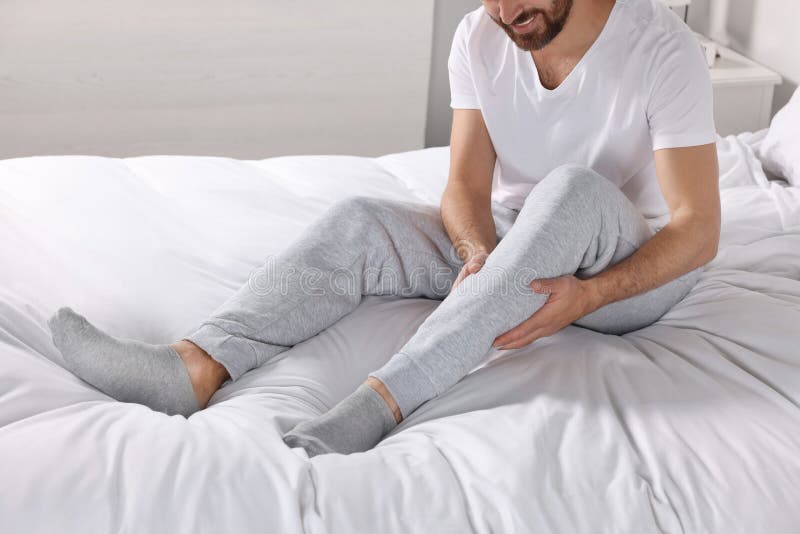 Man Suffering from Leg Pain on Bed at Home, Closeup Stock Image Image