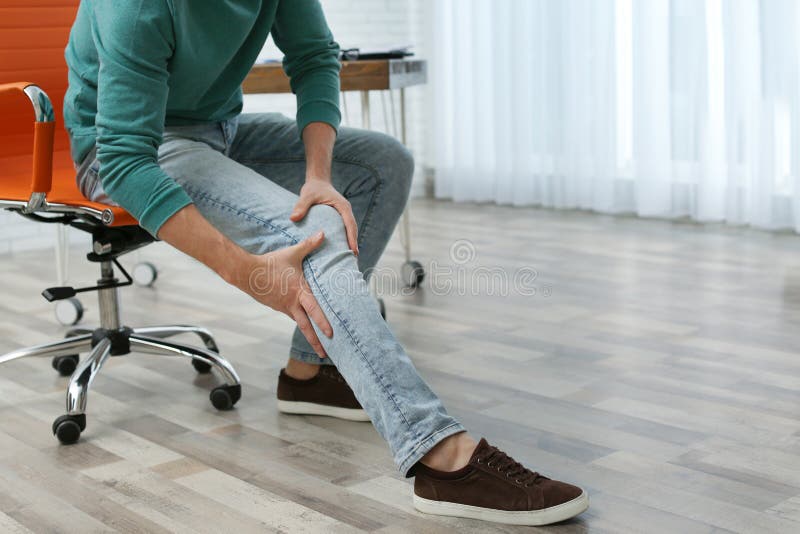 Man suffering from leg pain indoors with space for text